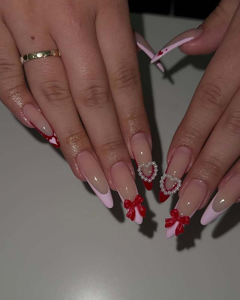 Pink French tips with red bows and pearl heart decorations