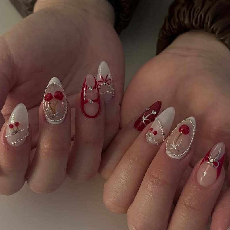 Nude nails with red cherries, bows and pearl-like dotted designs