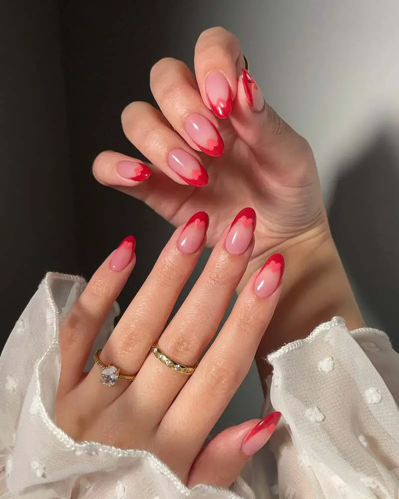 Nude nails with wavy red French tips in heart-inspired pattern