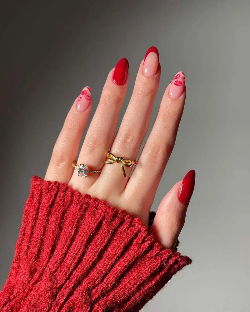 Nude and red French tip nails with delicate floral patterns in almond shape