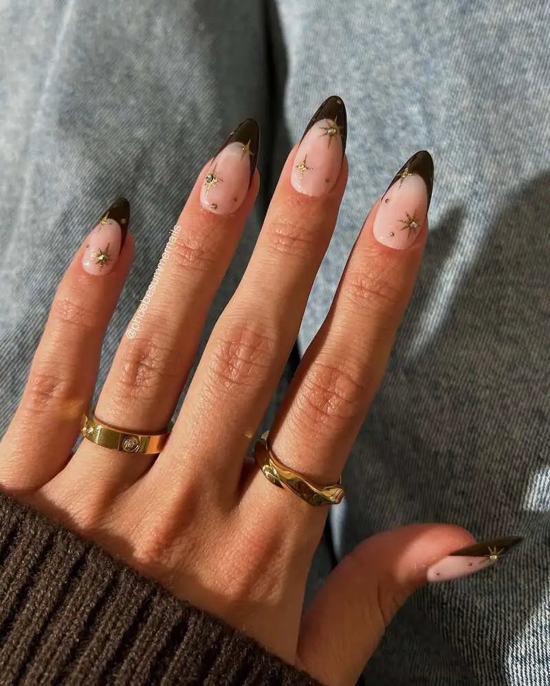 Nude nails with brown tips and gold star accents in celestial pattern