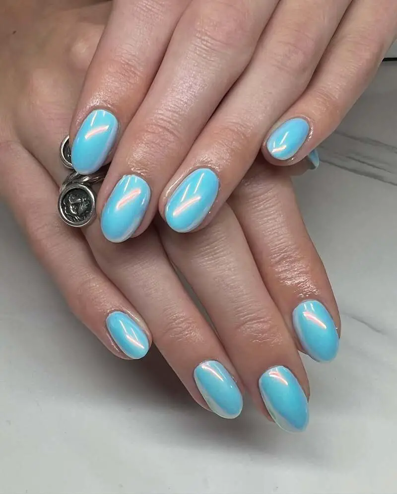 Oval-shaped nails with blue polish and chrome finish